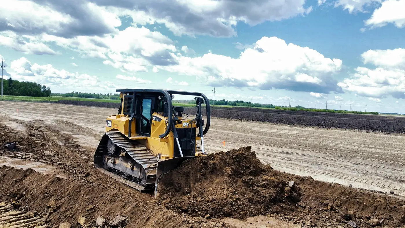 CAT D6T dozer pushing topsoil on a site preparation job